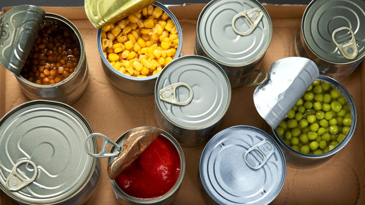 a variety of canned foods, opened, displaying the food inside such as peas, and corn