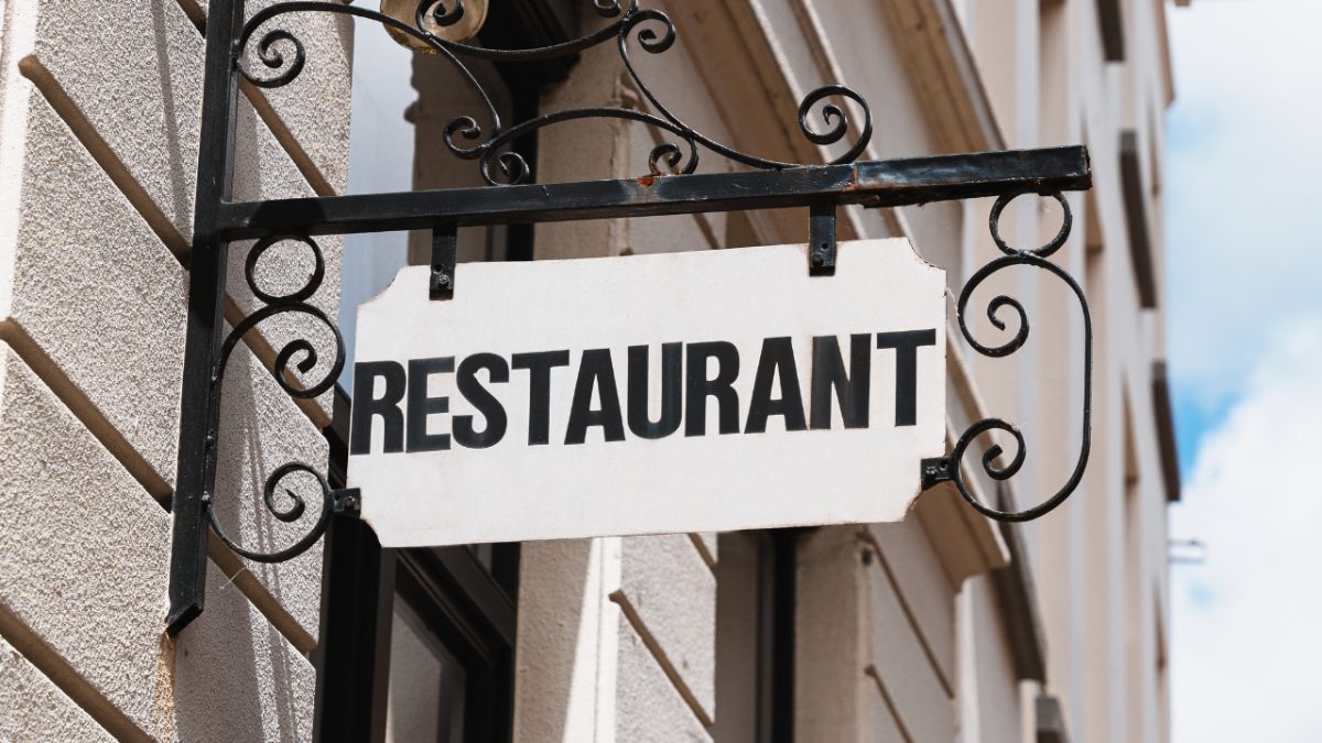 A fancy sign on the side of a concrete wall that says "restaurant"
