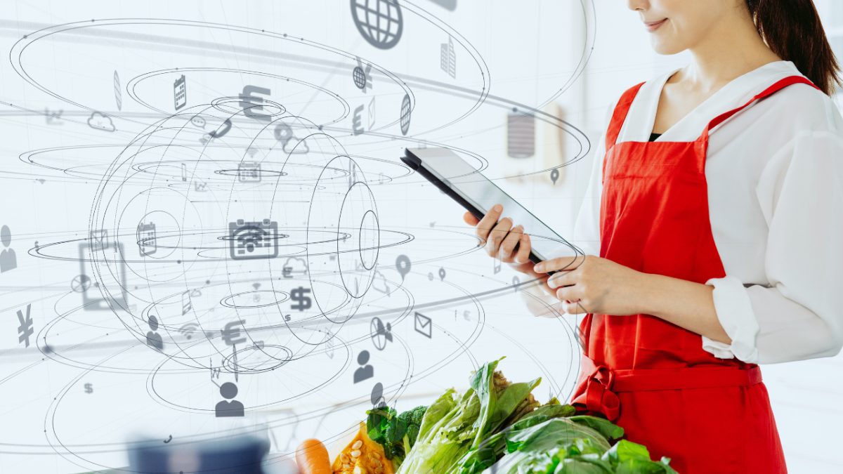 a girl in a red apron holding a tablet next to a bunch of veggies with augmented reality designs swirling around in the air in front of her