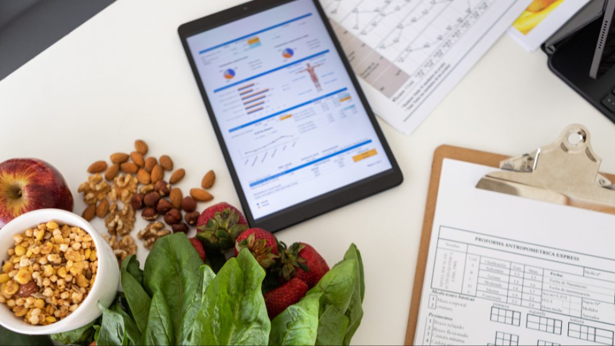 food, clipboard, and tablet with metrics displayed on a table