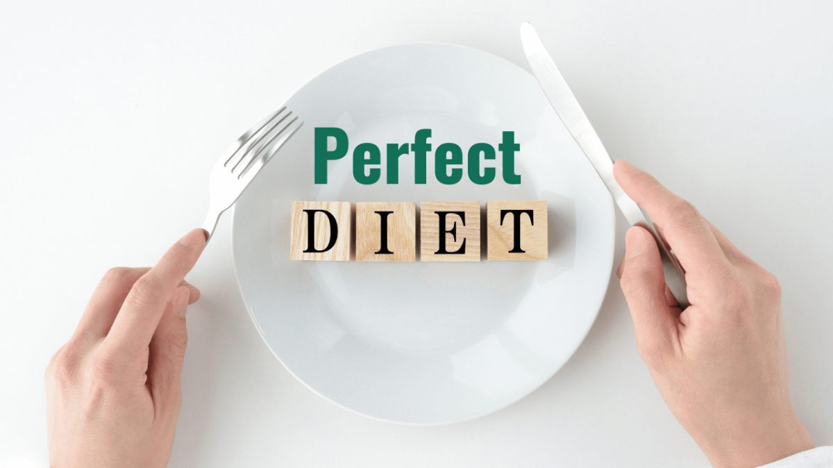 The word perfect written above the word diet spelled out on wooden blocks lined up on top of a white plate with a persons hands holding a knife and fork above to it